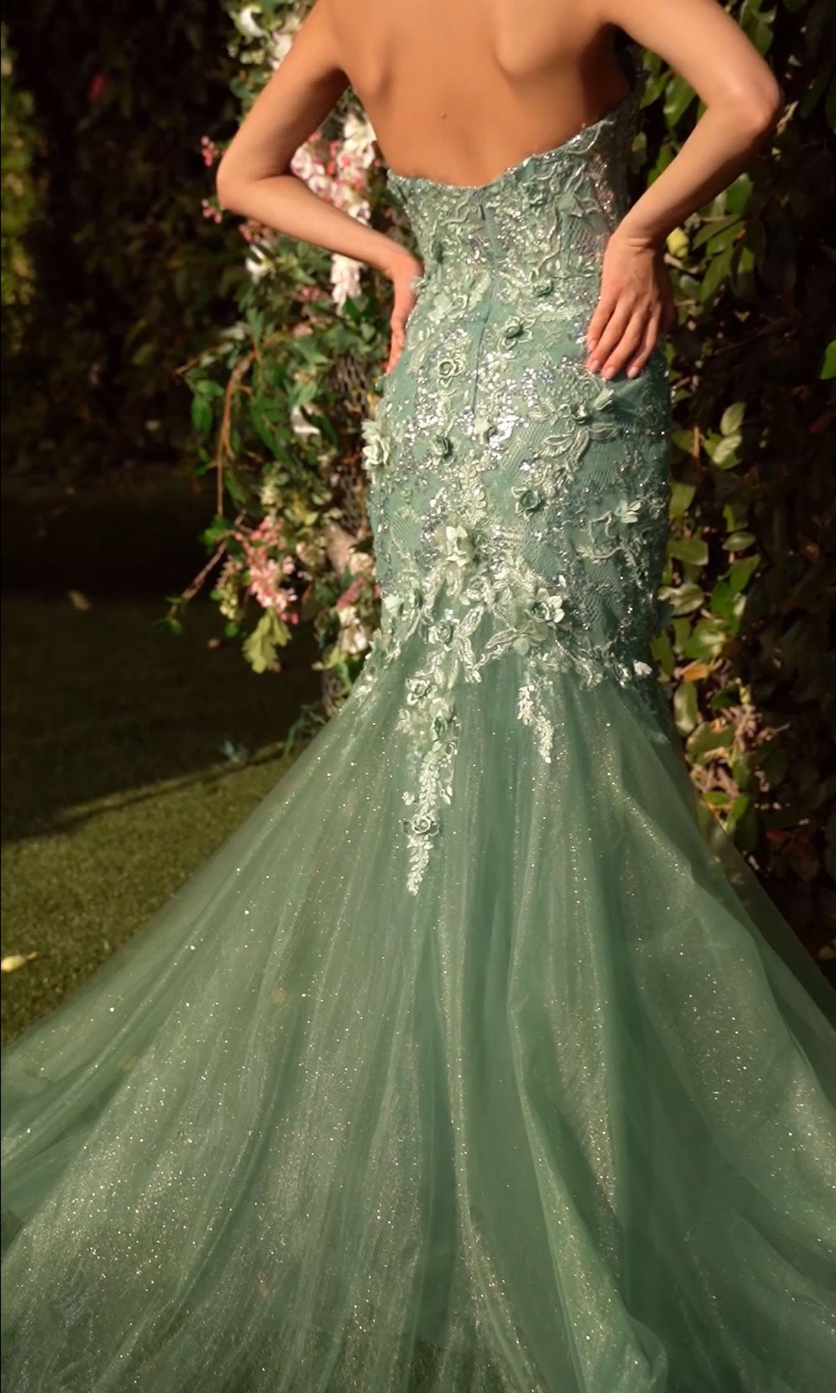 A woman wearing the Andrea & Leo MA101 long sleeve long formal dress stands outdoors near lush greenery.